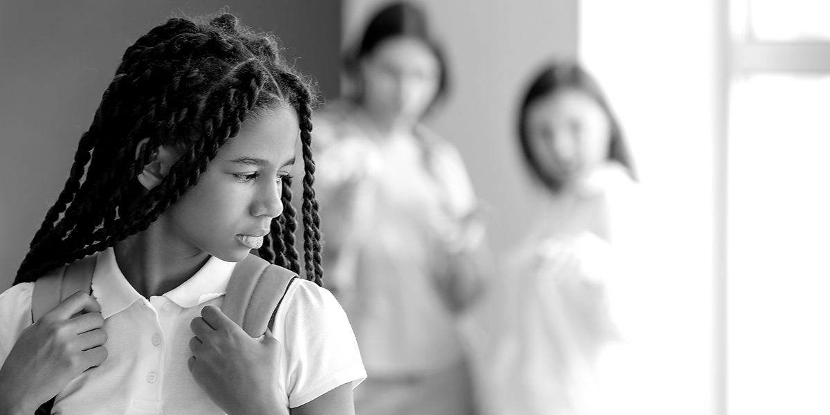 Image d'une jeune fille d'une minorité visible à l'école, avec son sac à dos, qui est pensive