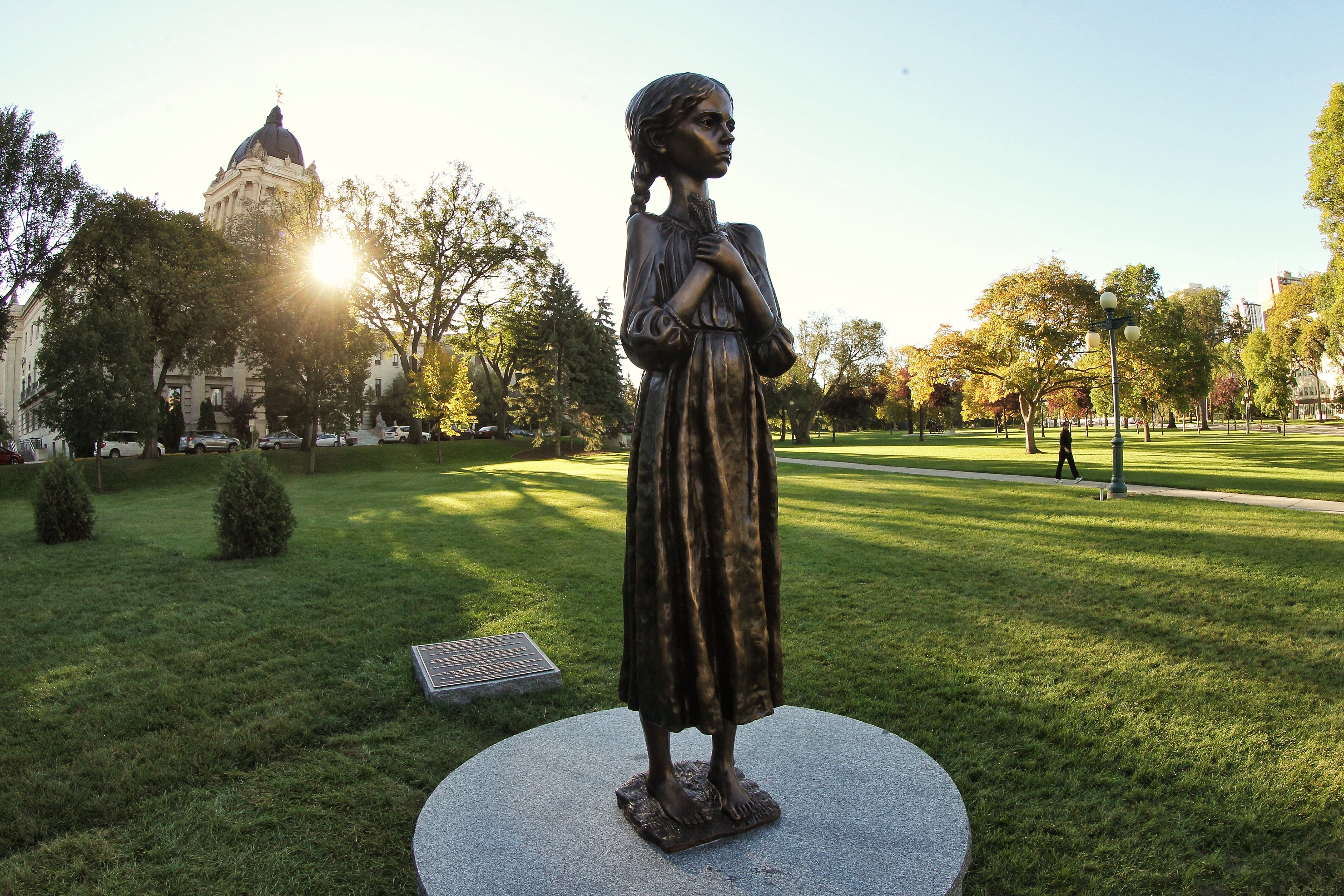 Statue de bronze d'une petite fille tenant du blé sur sa poitrine commémorant l'Holodomor, devant l'édifice de l'Assemblée législative du Manitoba, à Winnipeg